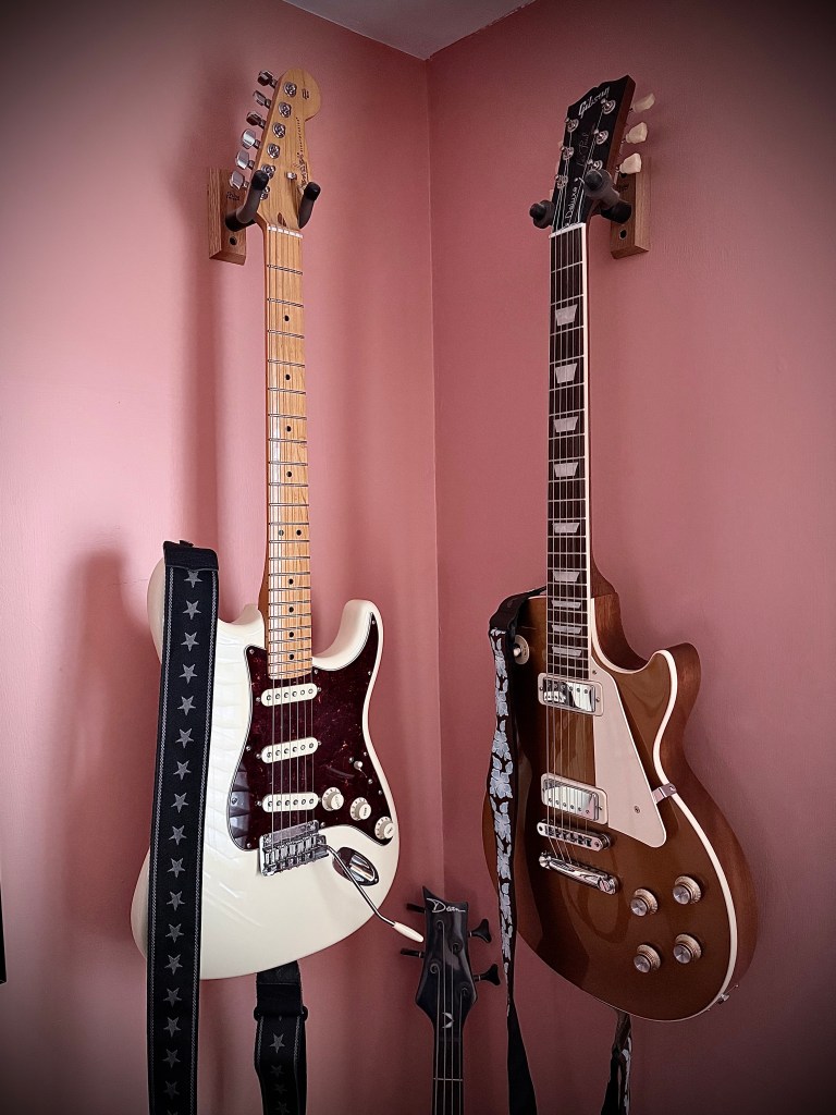 My two main guitars hanging on the wall: a Fender Stratocaster in Olympic White, and a Gibson Les Paul 70s Deluxe gold top